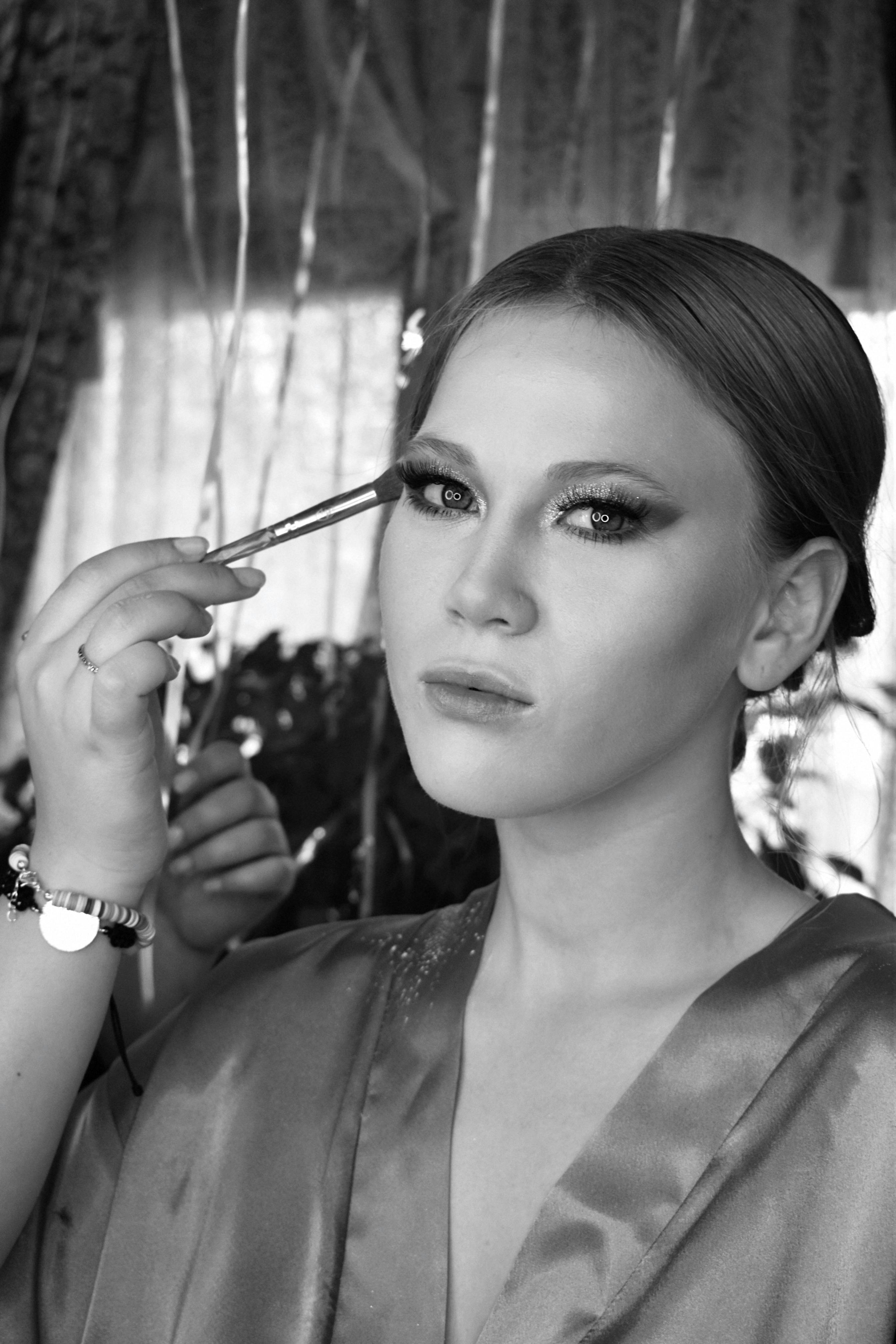 portrait of a beautiful woman with an artist finishing eye makeup