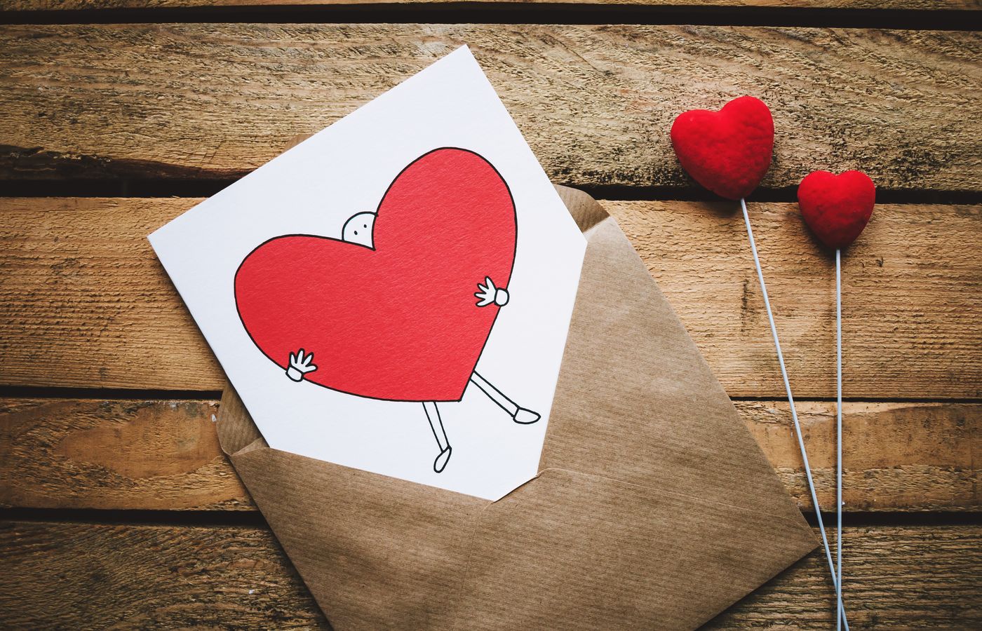 A love card with a red cartoon heart in an envelope on a rustic wooden table, perfect for Valentine's Day.