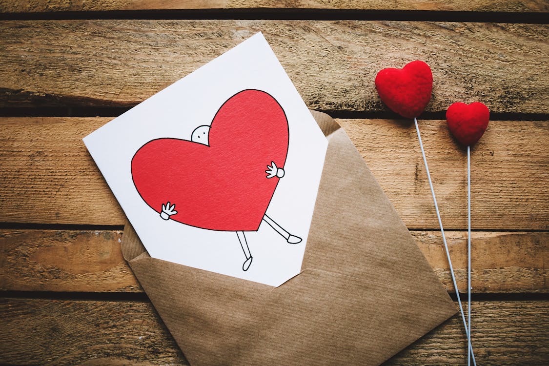 Free White, Black, and Red Person Carrying Heart Illustration in Brown Envelope Stock Photo