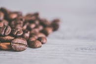 浅色木制表面上散落着芳香咖啡豆的详细特写