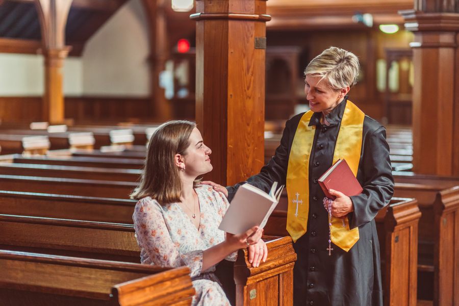 Two young adults reading and praying together in a church pew