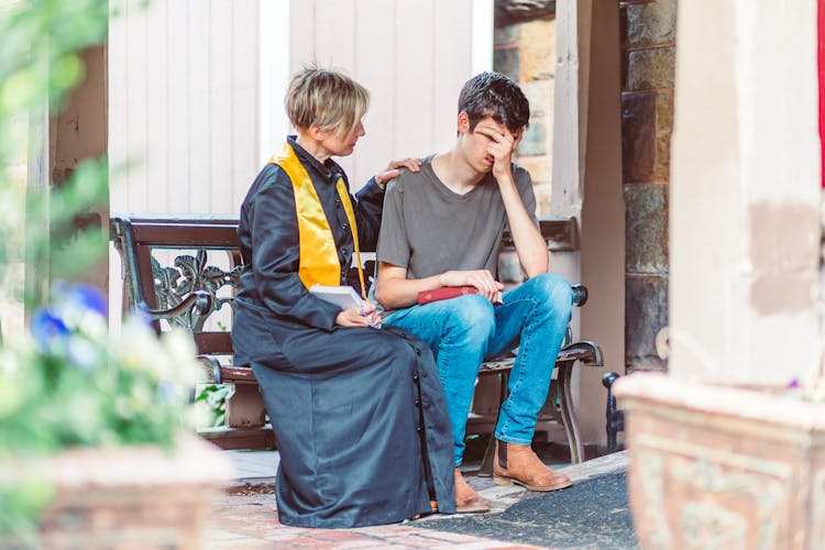 Woman Pastor Talking To Man While Sitting On Bench 