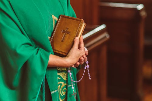 Free Priest carrying Bible and Rosary  Stock Photo