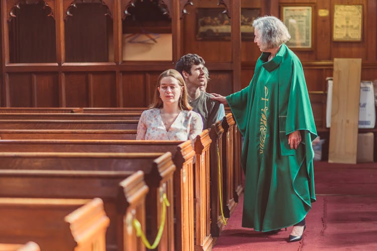 A Woman Priest Talking To Church Goers