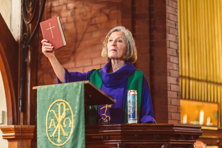 Female Priest On A Pulpit Holding A Bible 