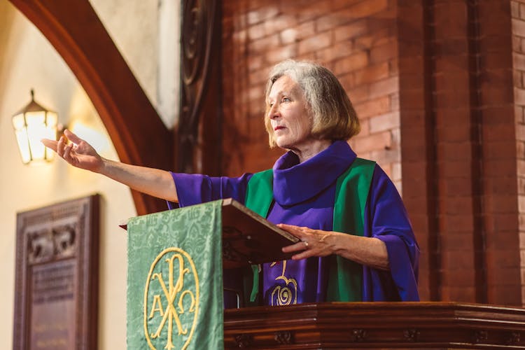 Woman Standing Behind A Lectern With Arm Extended