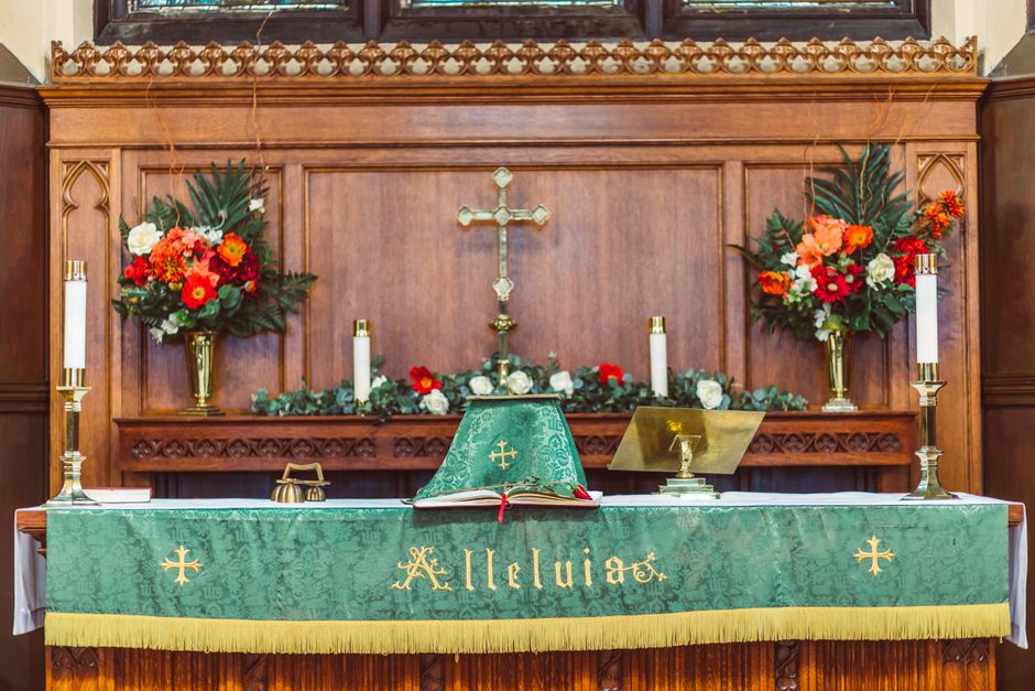 Altar de biserică decorat pentru Rusalii cu flori și lumânări
