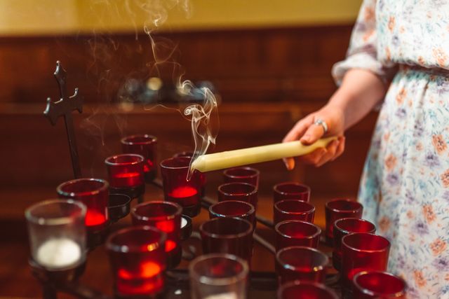 Hand steekt kaarsen aan in een kapel