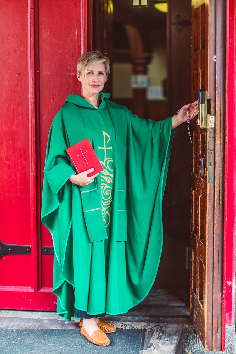 Female Priest In Green Robe Holding A Bible 