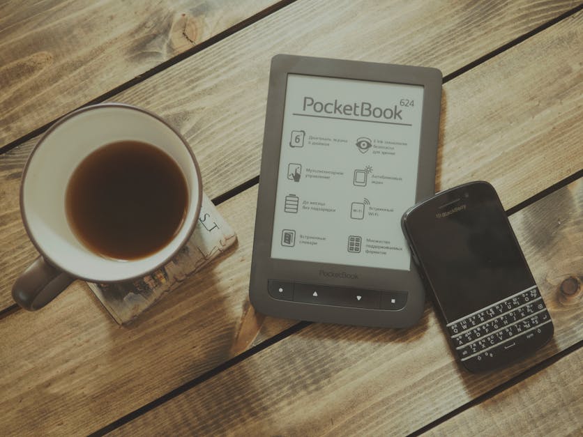 Blackberry Qwerty Phone Near Gray Pocket Book Case Beside Black Rim White Ceramic Teacup