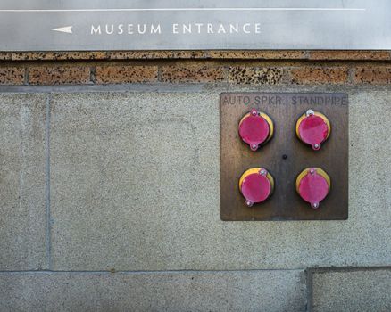 Exterior wall with museum entrance sign and fire standpipe connections.