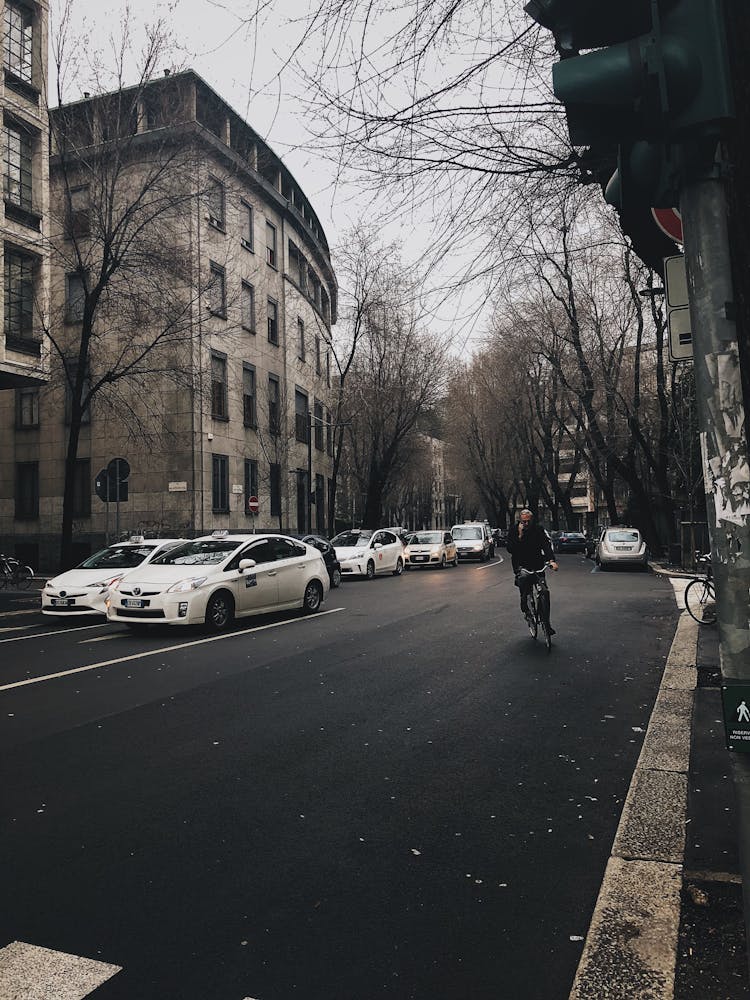 Person Riding A Bike Near The White Cars In The Street