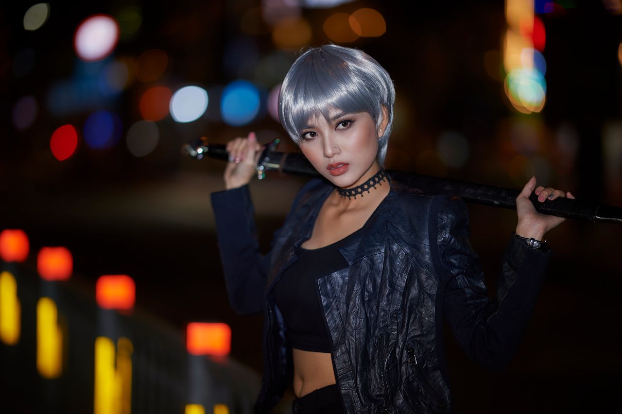 woman posing with sword and leather jacket at night featuring blurred