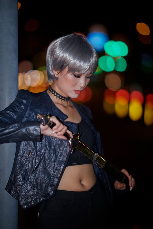 Free Stylish Asian woman with silver hair and leather jacket at night, holding a sword. Stock Photo