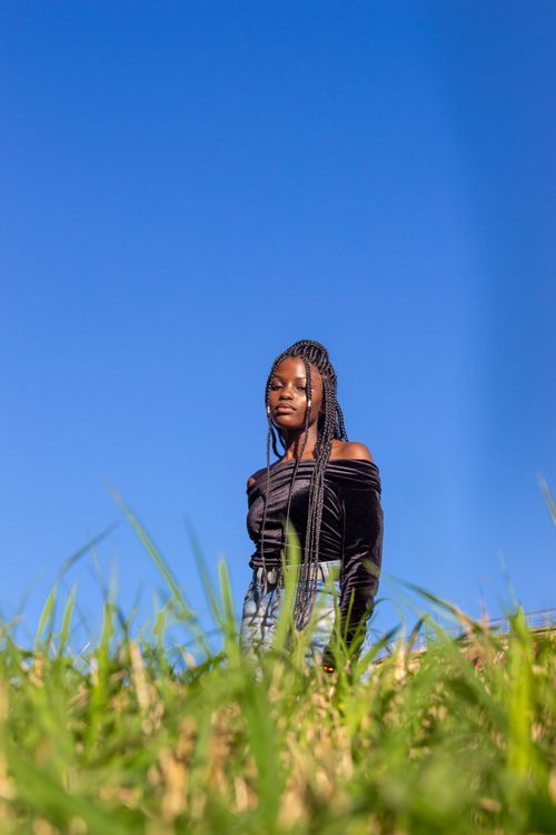 Free Outdoor portrait of a young woman in black attire against a striking clear blue sky. Stock Photo