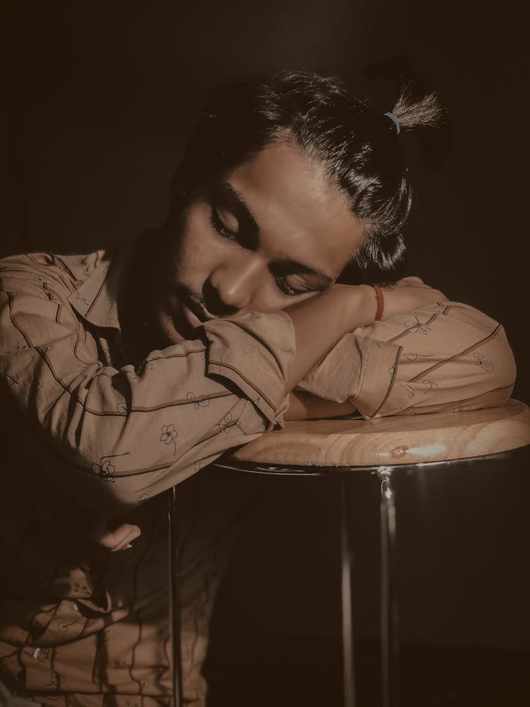 A Man In A Brown Long Sleeves Sleeping On A Chair