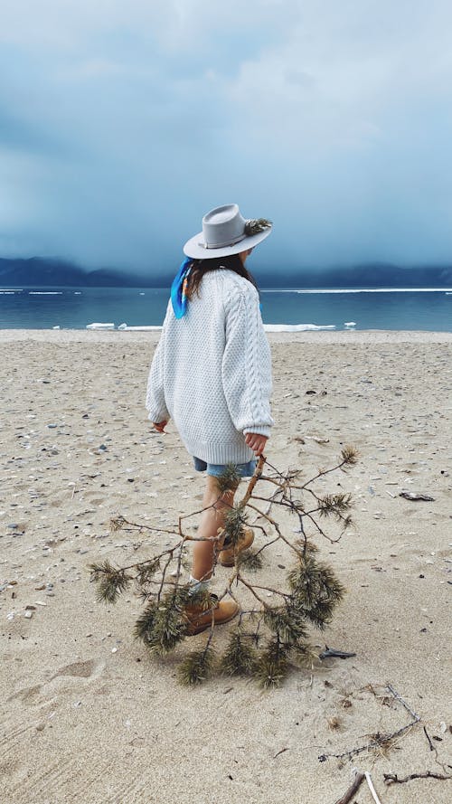 Woman in White Knitted Sweater Walking On Sand