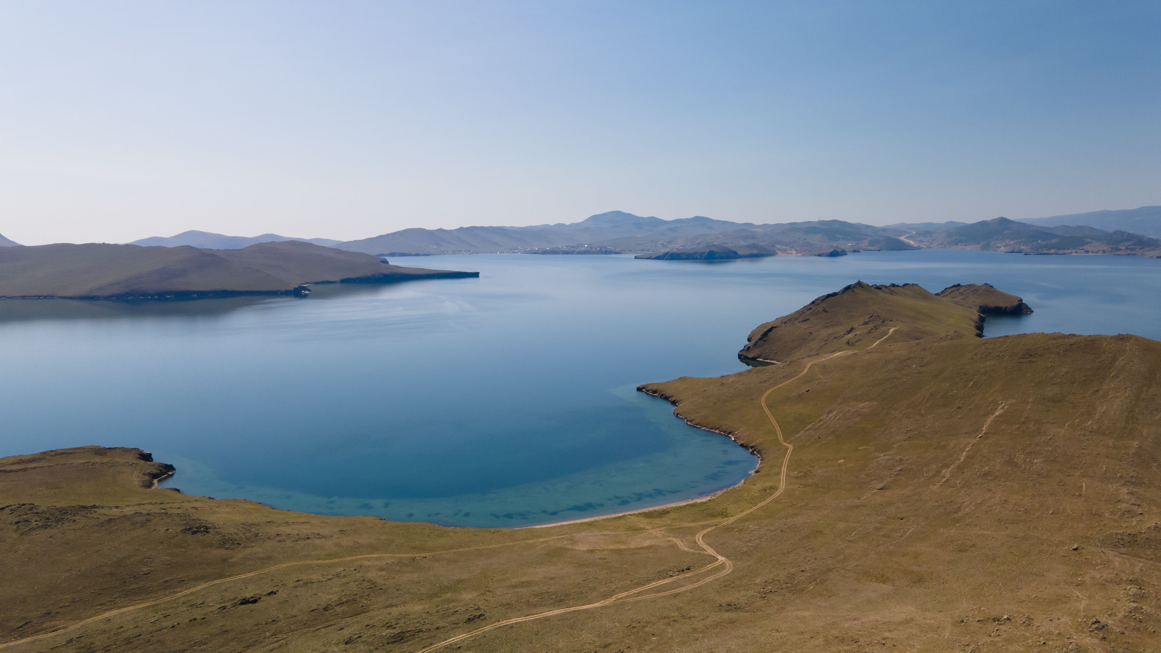 Stunning aerial view of Lake Baikal's coastline in Russia, showcasing vast blue waters and hilly landscapes.