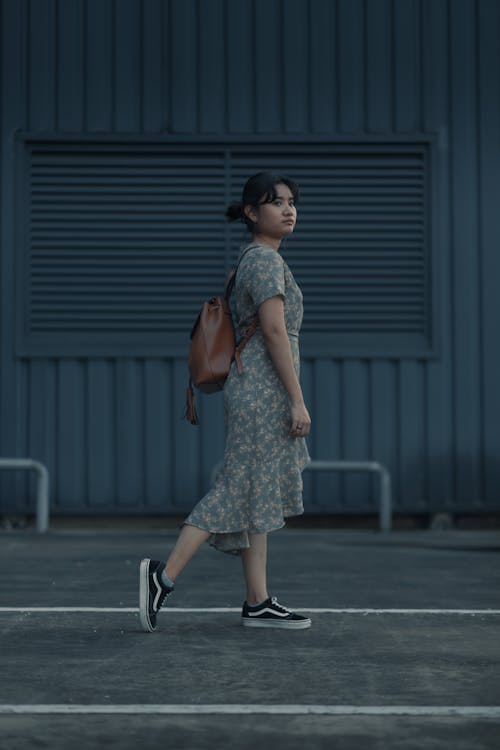 Photo of a Woman in a Green and Brown Dress Wearing a Brown Backpack