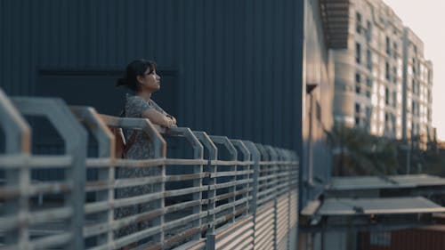 A Woman Standing Beside a Steel Railing Resting her Arms on the Handrail