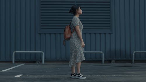 Photo of a Woman in a Green Floral Dress Standing on Concrete