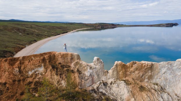 Aerial view of serene Lake Baikal with stunning rock formations and reflections under a cloudy sky.