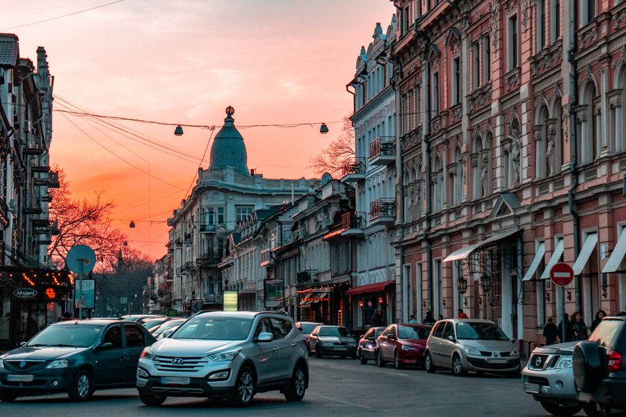 A bustling city street during sunset, showcasing classic architecture and vehicles.