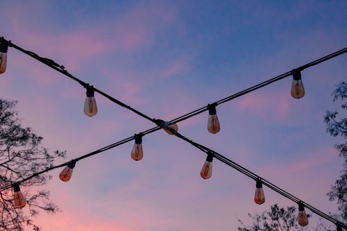 Free Outdoor string lights hanging with a colorful dusk sky in the background. Stock Photo