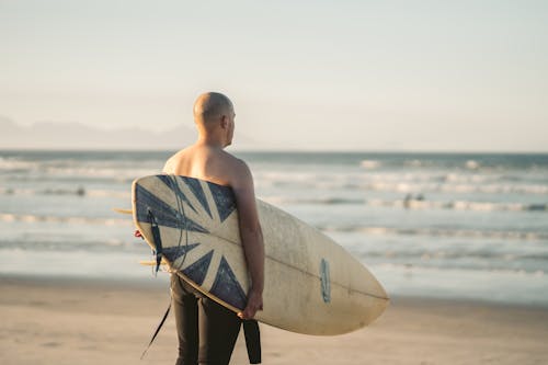 Back View of Man Carrying Surfboard