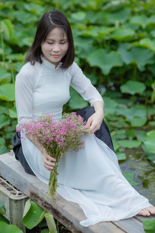 Free Woman in White Ao Dai Holding a Bouquet of Flowers Stock Photo