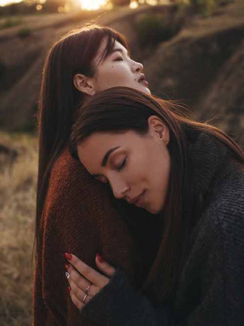 Free Two friends in a heartfelt embrace against a serene sunset background. Stock Photo