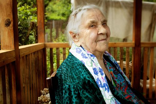 Free Portrait of a smiling senior adult woman sitting outdoors, conveying warmth and wisdom. Stock Photo