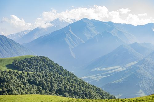 Free Scenic view of mountains and lush green hills under clear blue skies. Stock Photo