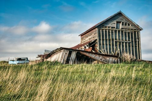 Free A rustic abandoned barn and old car in a grassy field in rural Minnesota, USA. Stock Photo