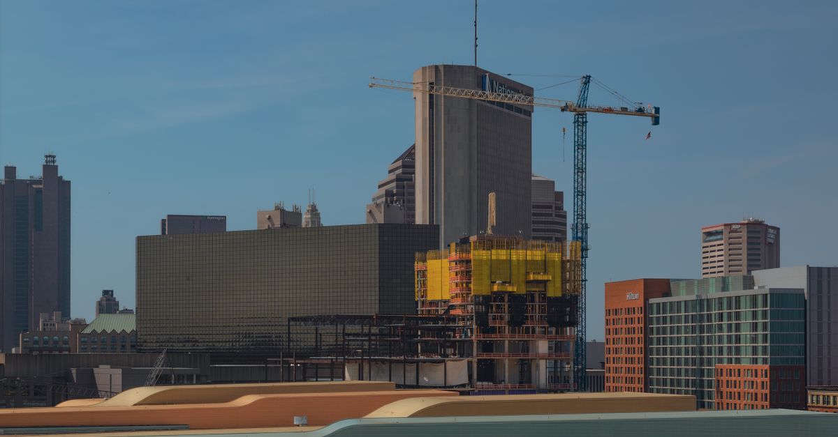 Dynamic urban skyline featuring construction cranes and modern architecture under a clear blue sky.