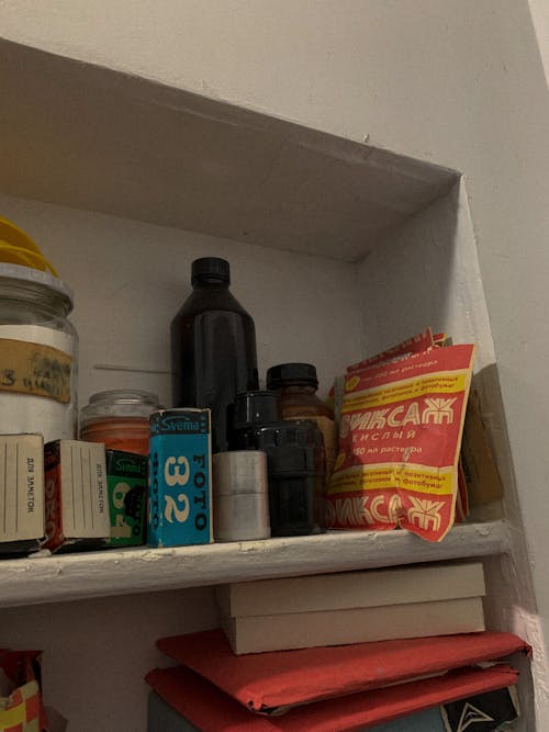 Assorted Plastic Containers and Boxes on White Wooden Shelf