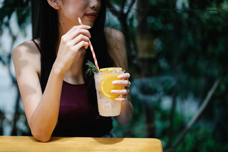 Woman Holding An Orange Lemonade Drink In Plastic Cup