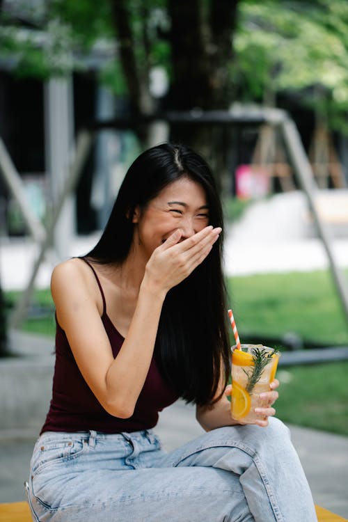 Free A Woman is Laughing While Covering Her Mouth Stock Photo