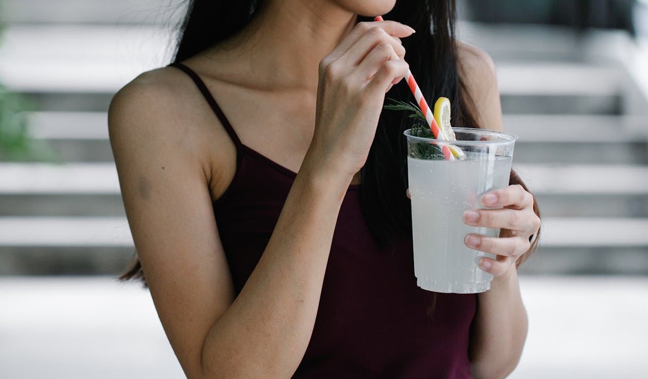 Close-Up Photo of a Woman Holding a Refreshing Drink in a Plastic Cup