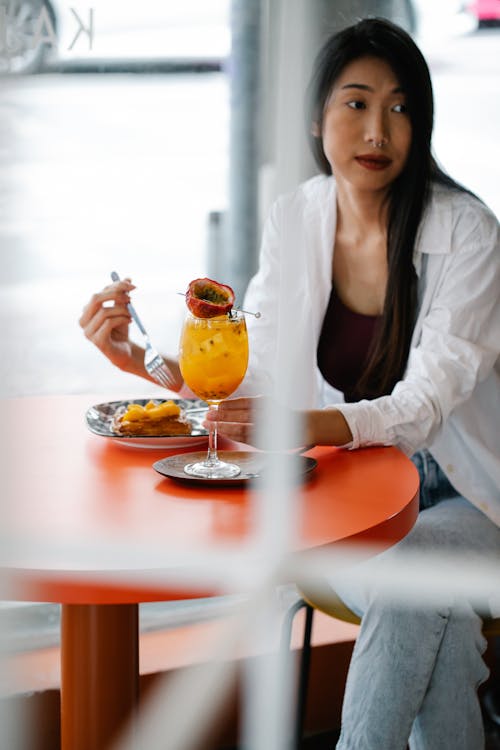 Woman Sitting By The Table Having Snack With A Pomegranate Juice