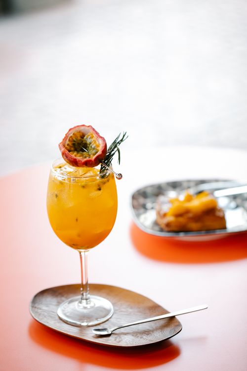 Free Orange passion fruit cocktail in a glass with dessert in a cozy setting. Stock Photo