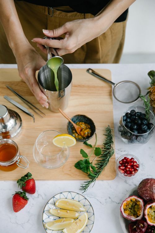 Free Hands preparing a colorful fruit cocktail with fresh ingredients and garnishes on a wooden board. Stock Photo