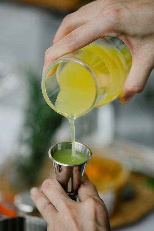 A Person Pouring Juice on a Jigger