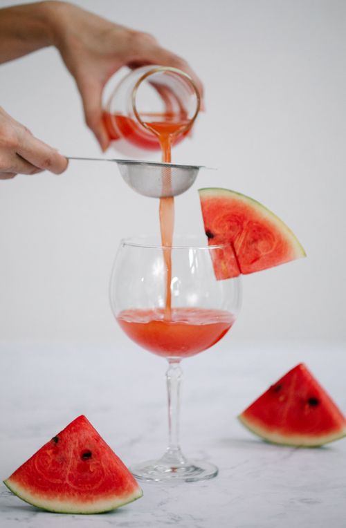 Free Refreshing watermelon juice being poured through a strainer into a wine glass with watermelon slices. Stock Photo