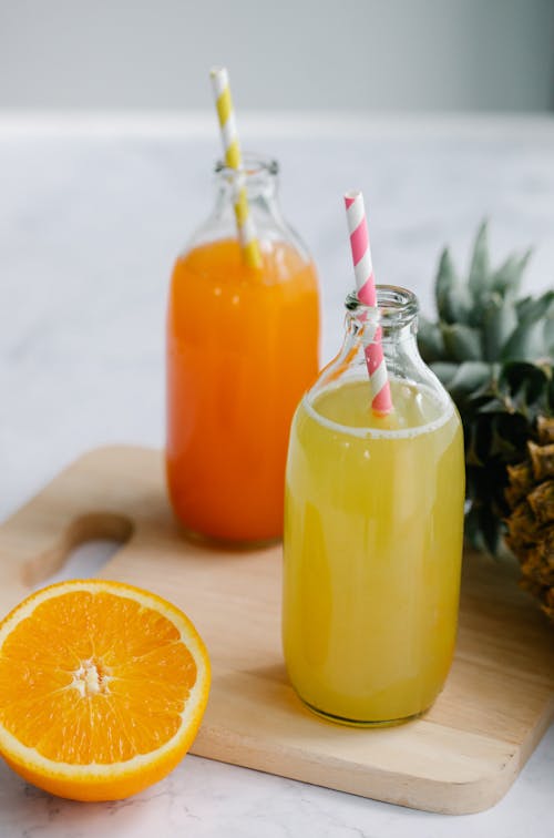 An Orange and Pineapple Juice in Glass Bottles