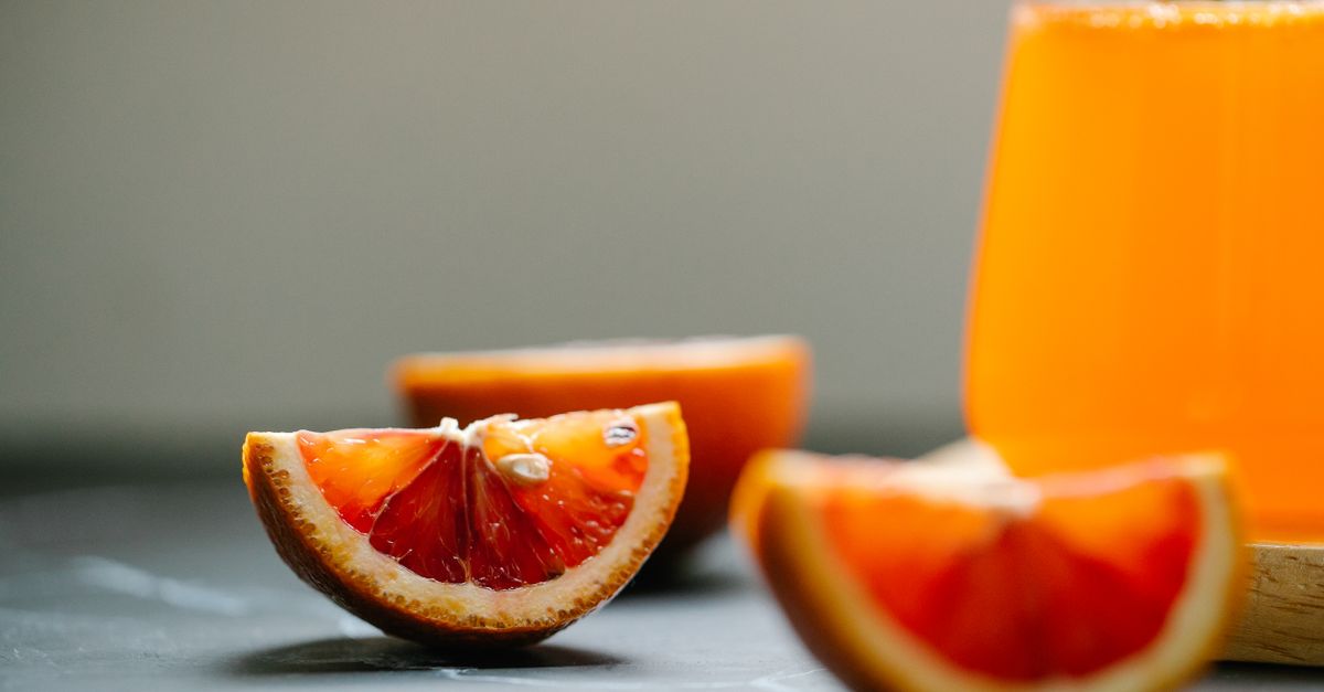 Vibrant close-up of freshly sliced oranges next to a glass of orange juice, highlighting their juiciness and freshness. - Evidence evidence guide for orange juice blood pressure randomized trial