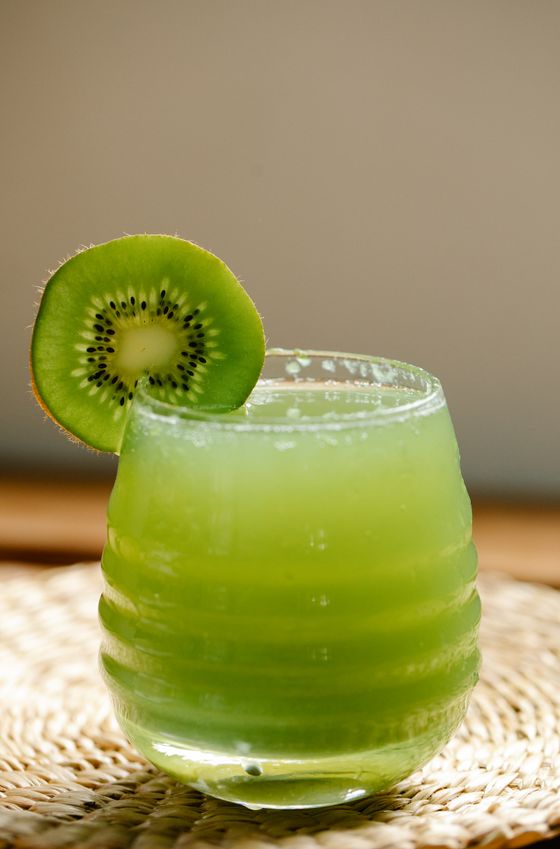 Vivid green kiwi drink in a ribbed glass with a kiwi slice on the rim