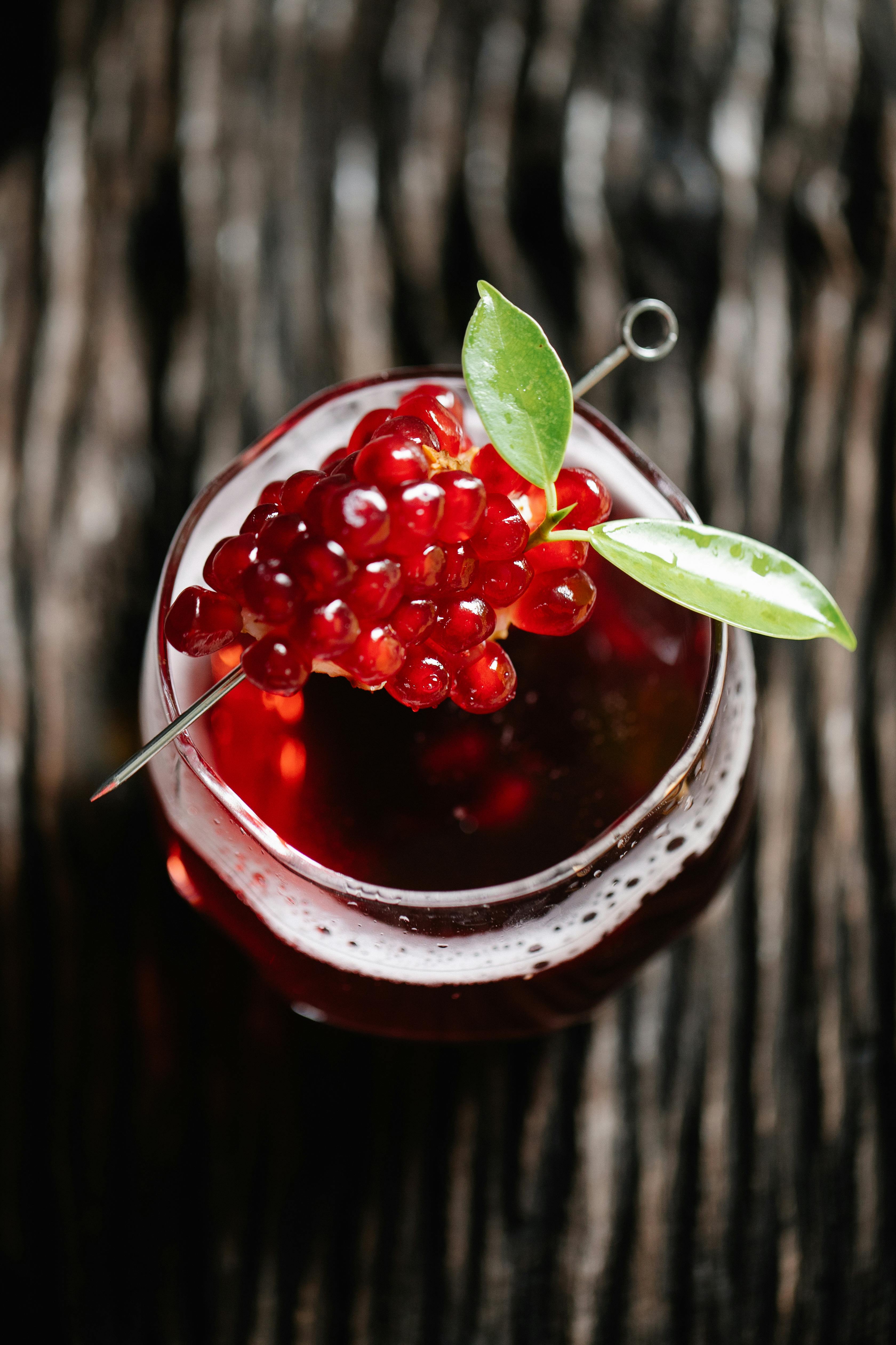 Top-down view of a vibrant pomegranate cocktail garnished with leaves, perfect for a refreshing drink idea.