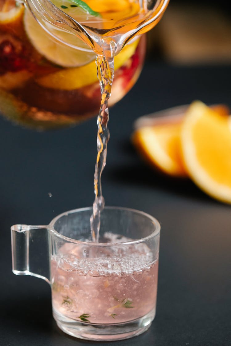 A Person Pouring A Drink Into A Glass