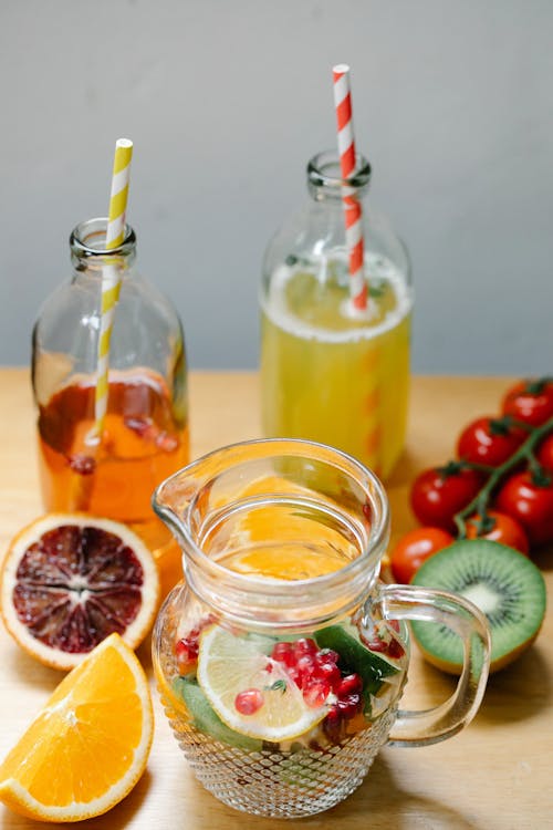 A Glass Pitcher Near the Fruits and Glass Bottles with Drinking Straws